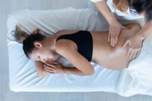 Woman receiving pregnancy massage, laying on her side.
