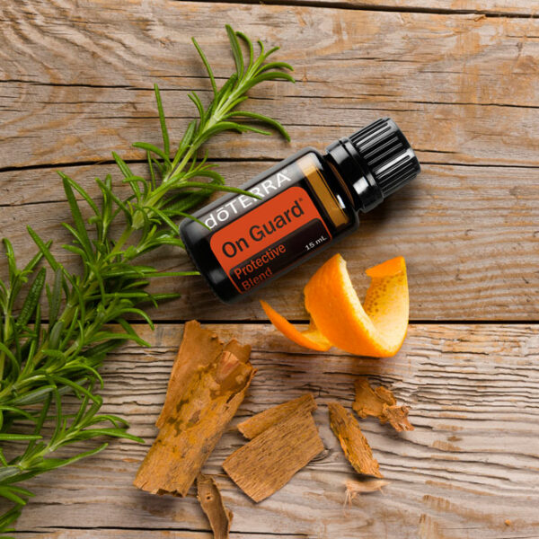 doTerra On Guard essential oil 15ml vial on a table with some orange peel and spices.